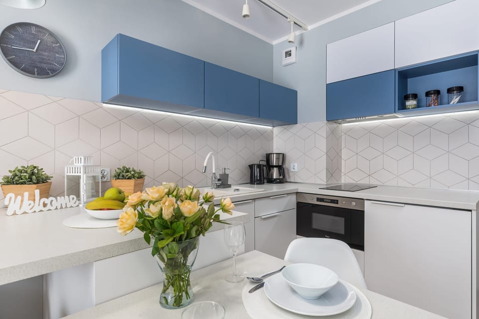 A beautiful kitchen with a blue and white color scheme, featuring modern cabinets, a large countertop, and decorative plants for a fresh look.