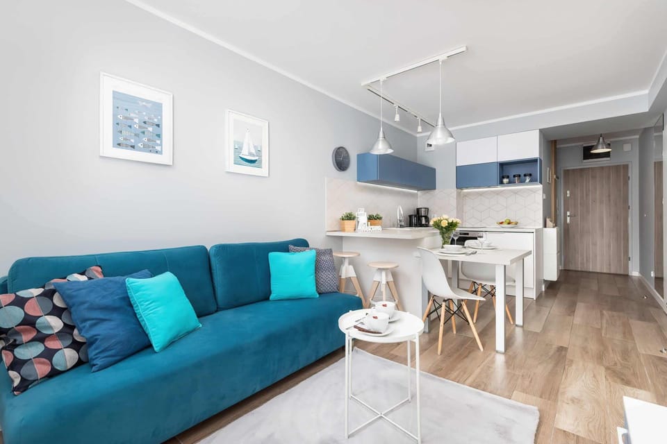 A modern living room decorated in shades of blue and white, featuring a cozy blue sofa with matching pillows, a minimalist coffee table, and bright natural lighting from large windows.