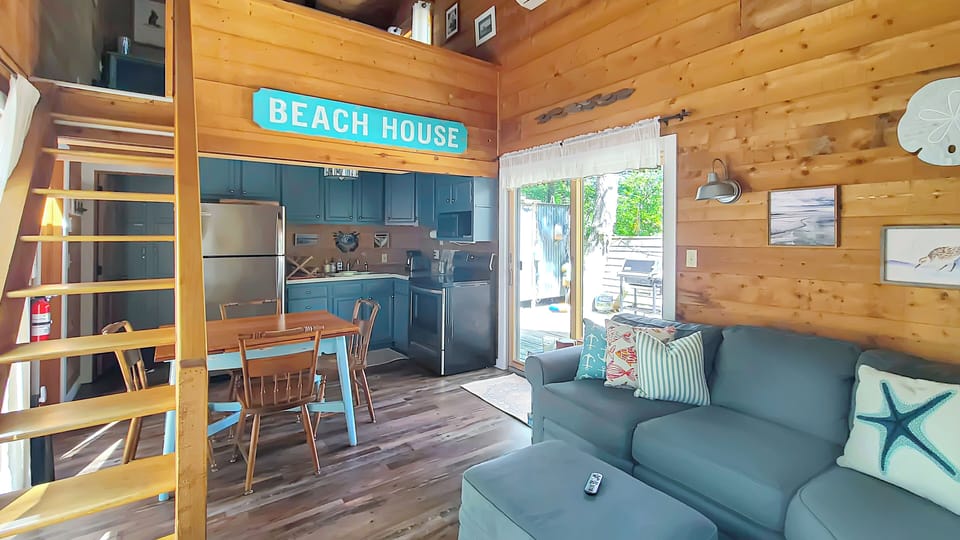 Living room with kitchen and slider to private back deck beyond