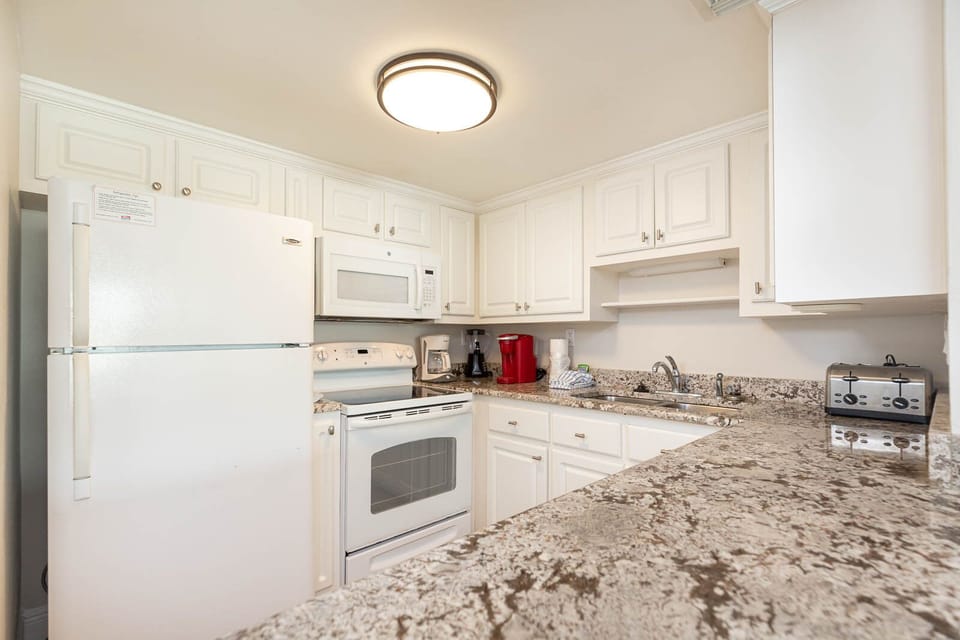 The kitchen features white cabinets, granite countertops, and modern appliances, perfect for preparing meals during your stay