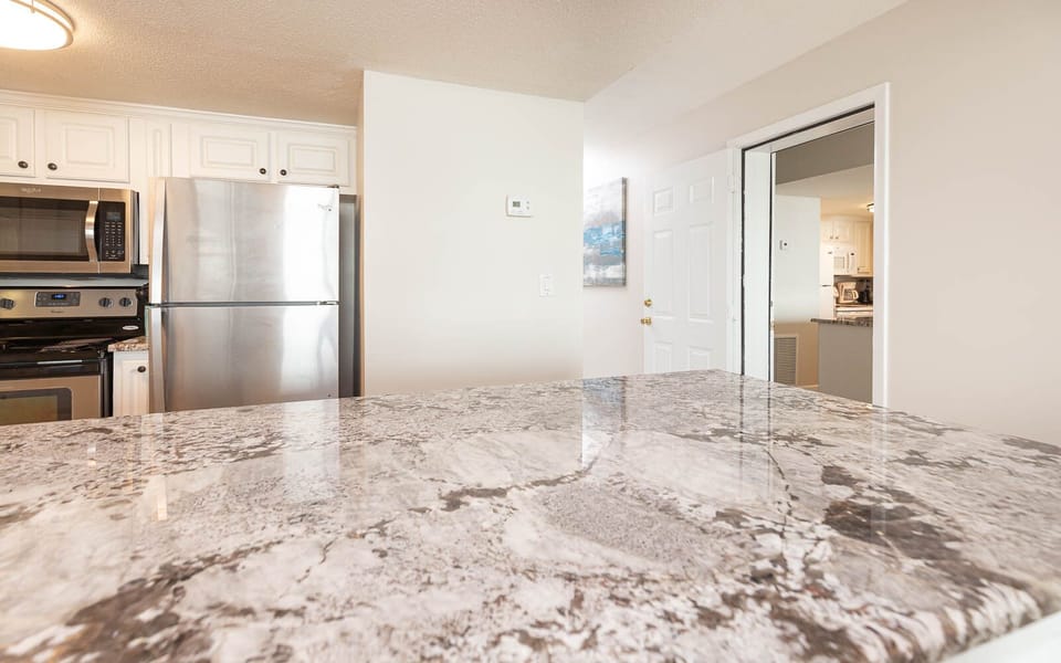 This kitchen features sleek stainless appliances, granite countertops, and a welcoming view of the adjacent living area