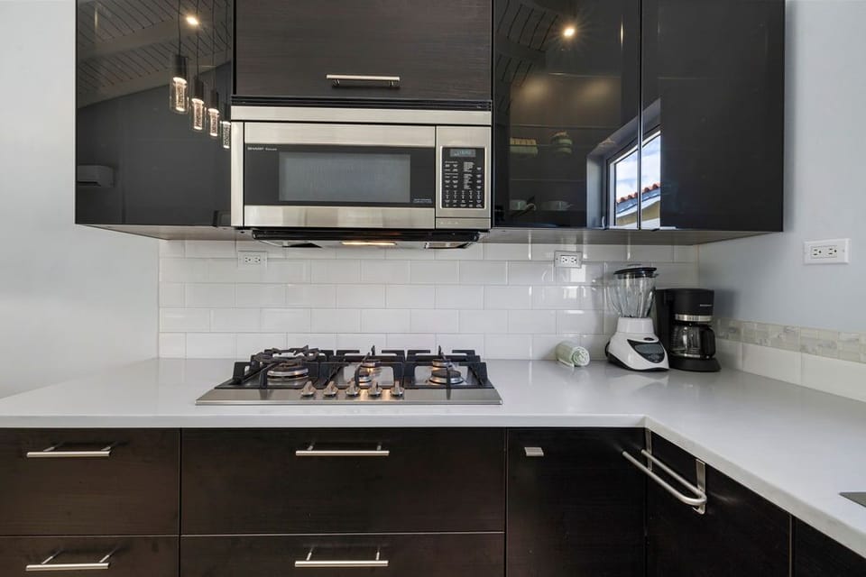 Modern kitchen complete with all necessary appliances ie. stove, coffee maker, blender, microwave and fridge.