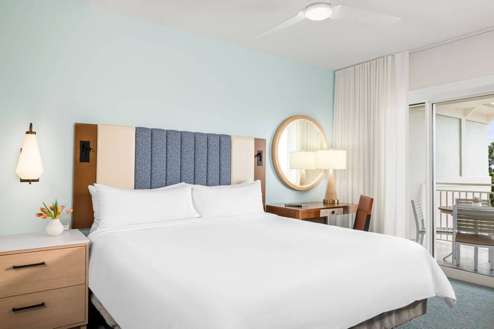 Primary bedroom features a king size bed, desk, ensuite bath, and private door to the furnished patio.