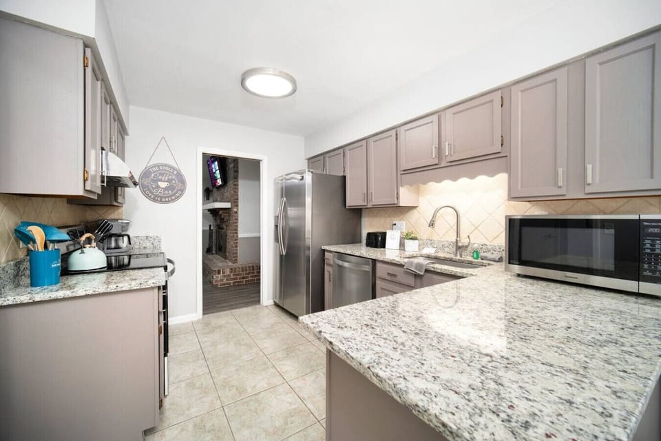 This modern kitchen offers plenty of counter space, sleek stainless-steel appliances, and a cozy view into the living area.