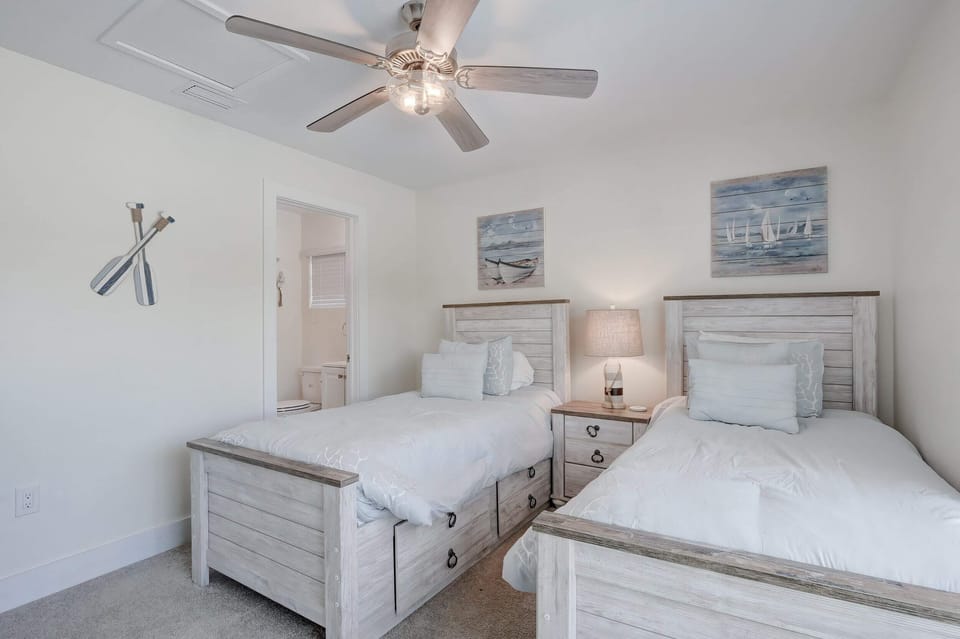 The Second Bedroom Contains 2 Twin Beds, a Nightstand and Lamp, a Ceiling Fan and A En Suite Bathroom