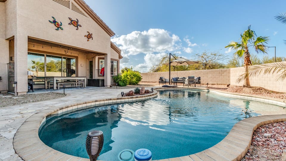 Close up from fire pit looking at pool, billiards, and out door furniture