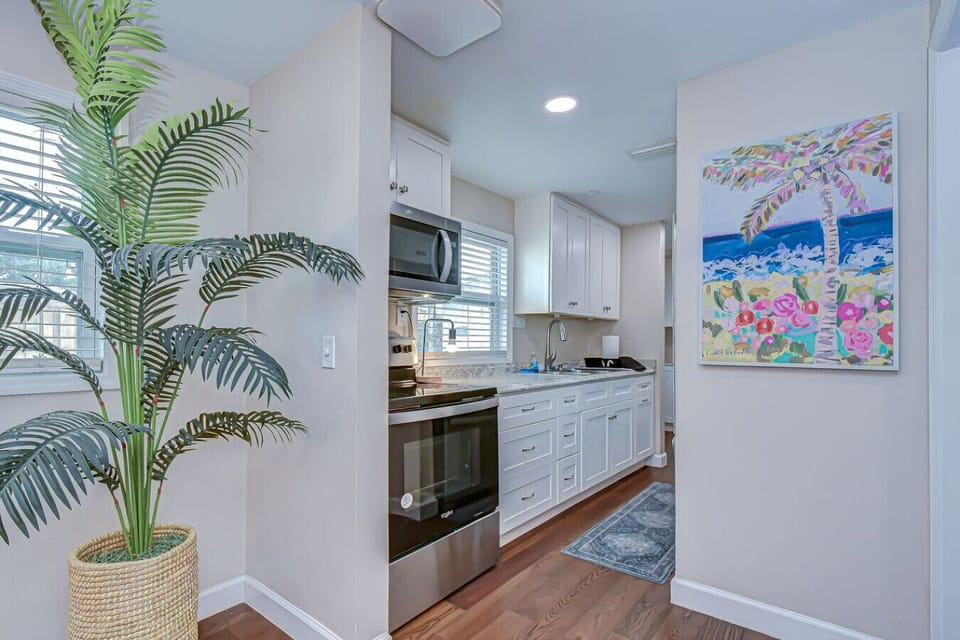 This charming kitchen opens up beautifully with natural light and coastal artwork for a cheerful vibe.