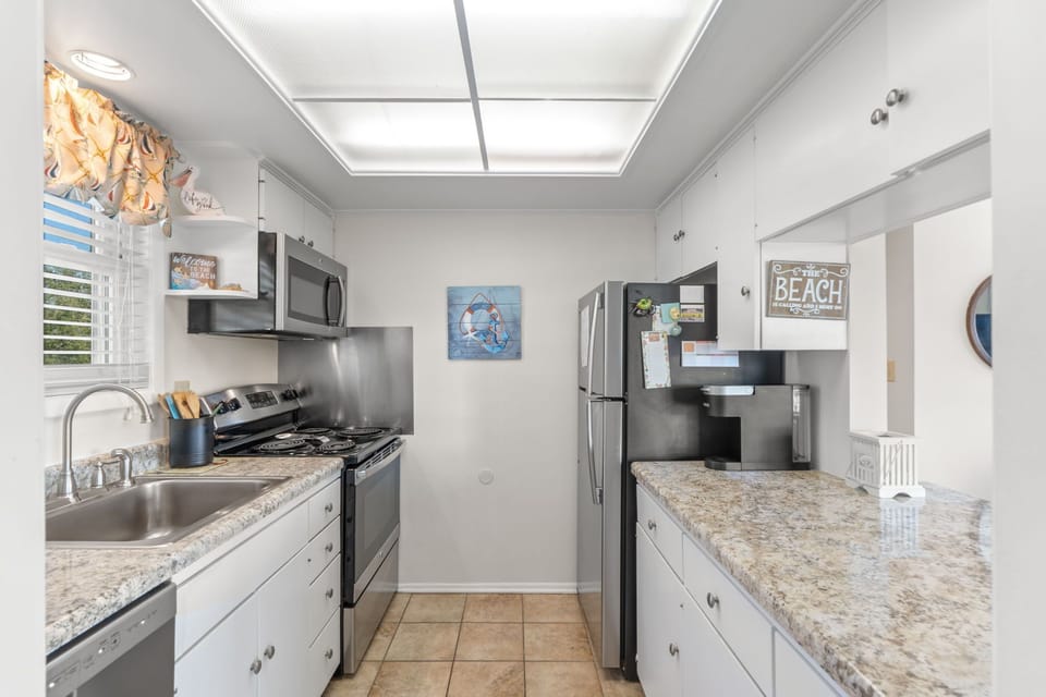 Your fully-equipped galley kitchen invites culinary adventures with granite counters, stainless appliances, and cheerful beach-themed touches throughout.