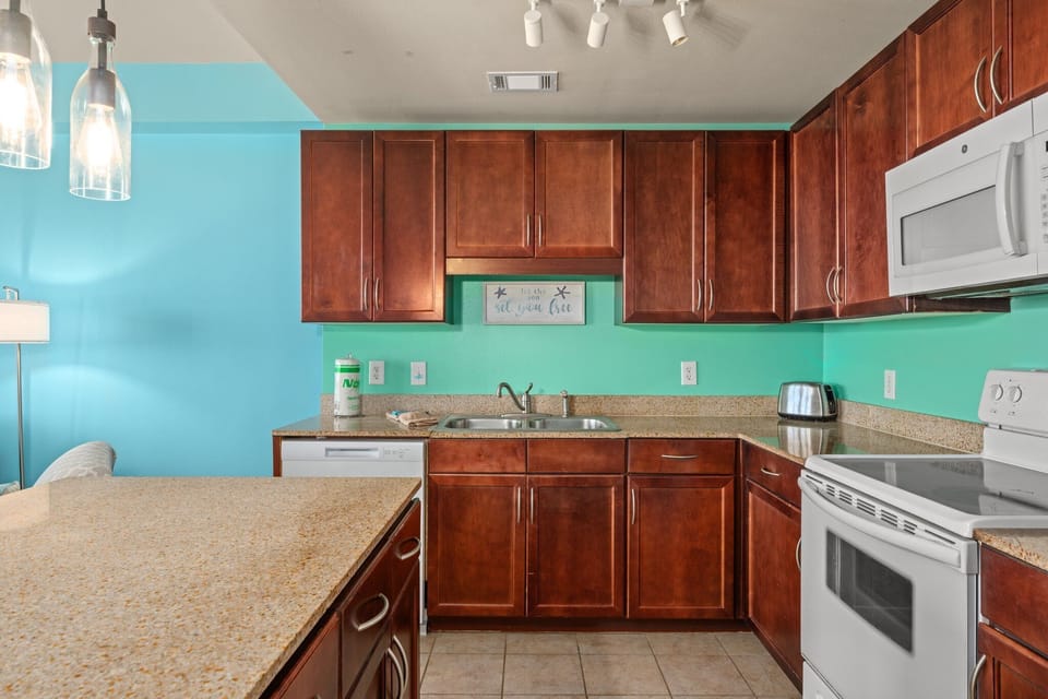 Full kitchen with track lighting, microwave, oven, stove, dishwasher. 