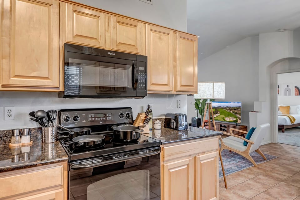 Fully stocked kitchen with cookware, dinnerware, and utensils.