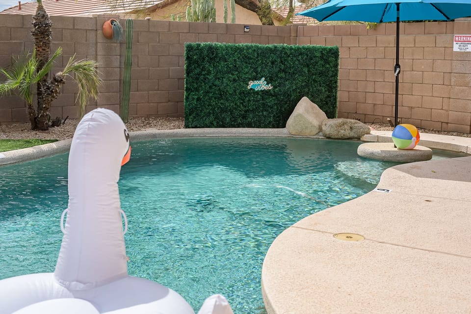 Swimming pool with inflatable toys and photo backdrop.