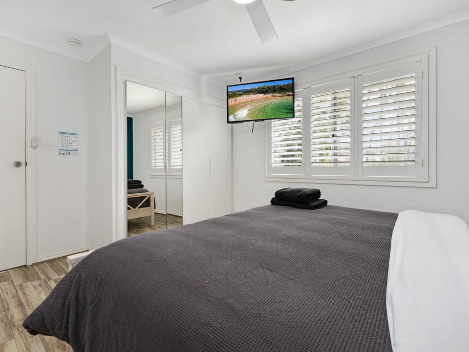 Bedroom 1 - Main King Bedroom - Upstairs : Skye’s Beach House Malua Bay includes an upstairs main king bedroom as part of the four-bedroom upper level, near the upstairs living and dining areas.