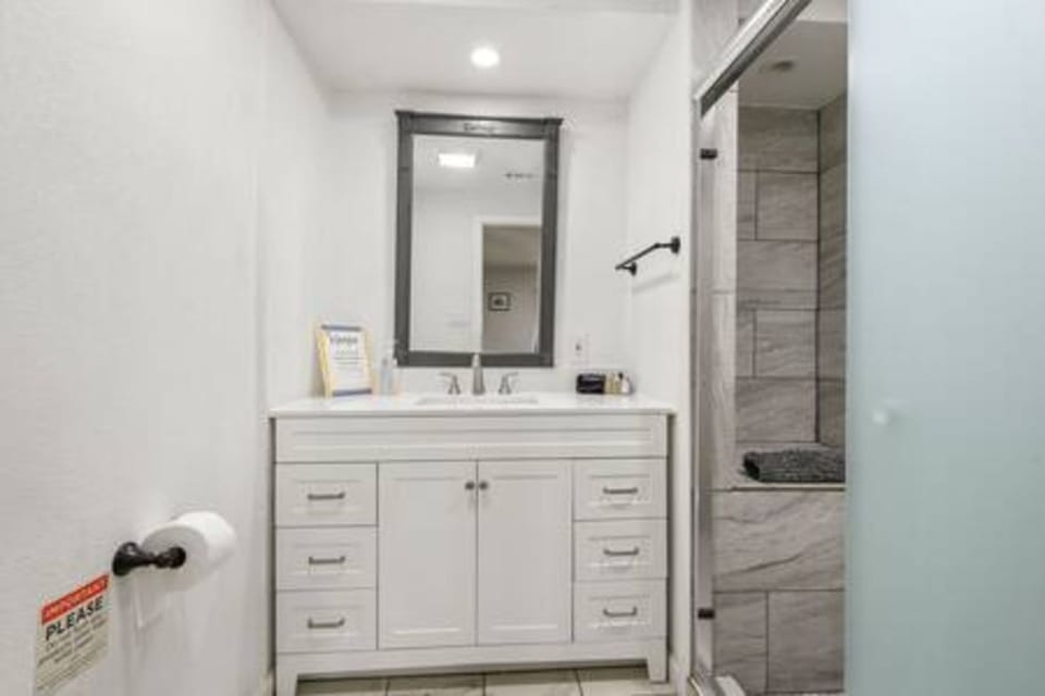 Step into your pristine bathroom where modern elegance meets comfort. Crisp white vanity and marble-tiled shower await your daily refresh.