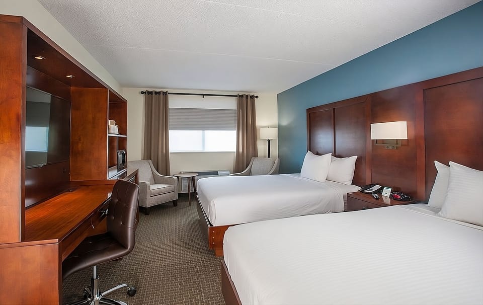 Unwind in a spacious double-queen room with cozy lounge seating.