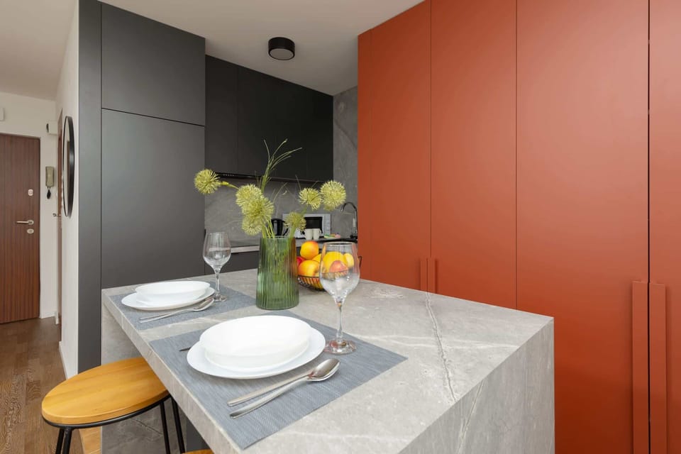 A compact kitchen with red cabinetry, a breakfast bar, and modern appliances.
