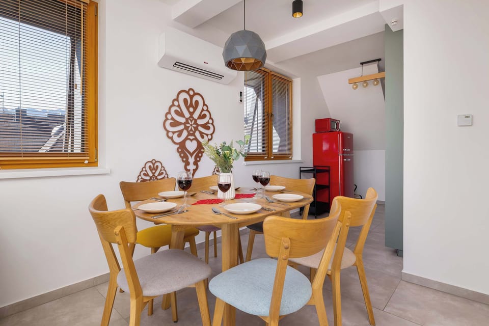 A dining area with a wooden table and chairs, next to a window with natural light and mountain-inspired décor.