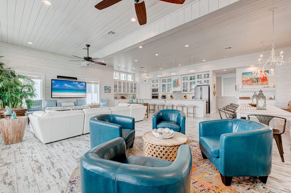 Relax in your elegant open-concept living space with turquoise leather seating, modern kitchen, and coastal charm throughout.