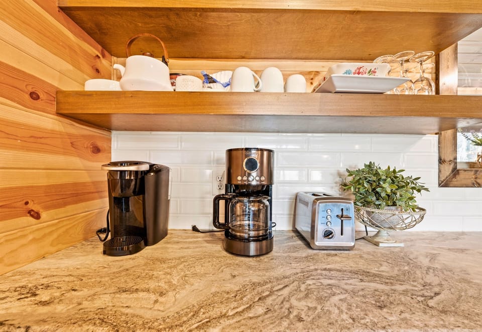 A close-up of a well-equipped beverage station featuring a sleek coffee maker and a variety of mugs, neatly arranged on a wooden countertop