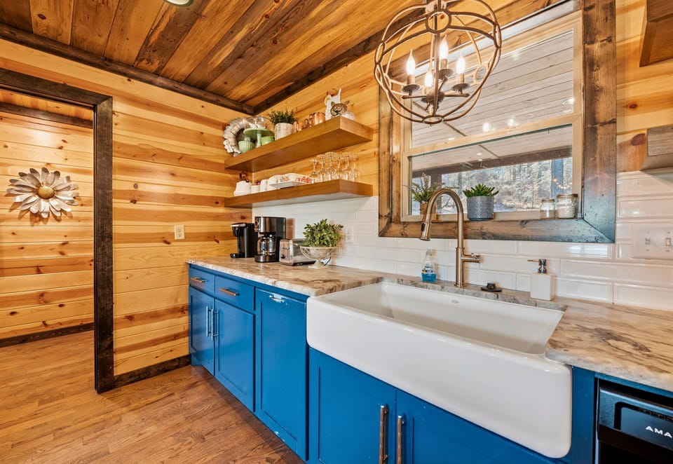A charming kitchen corner with bold blue cabinets and a large farmhouse sink, complemented by an overhead circular chandelier