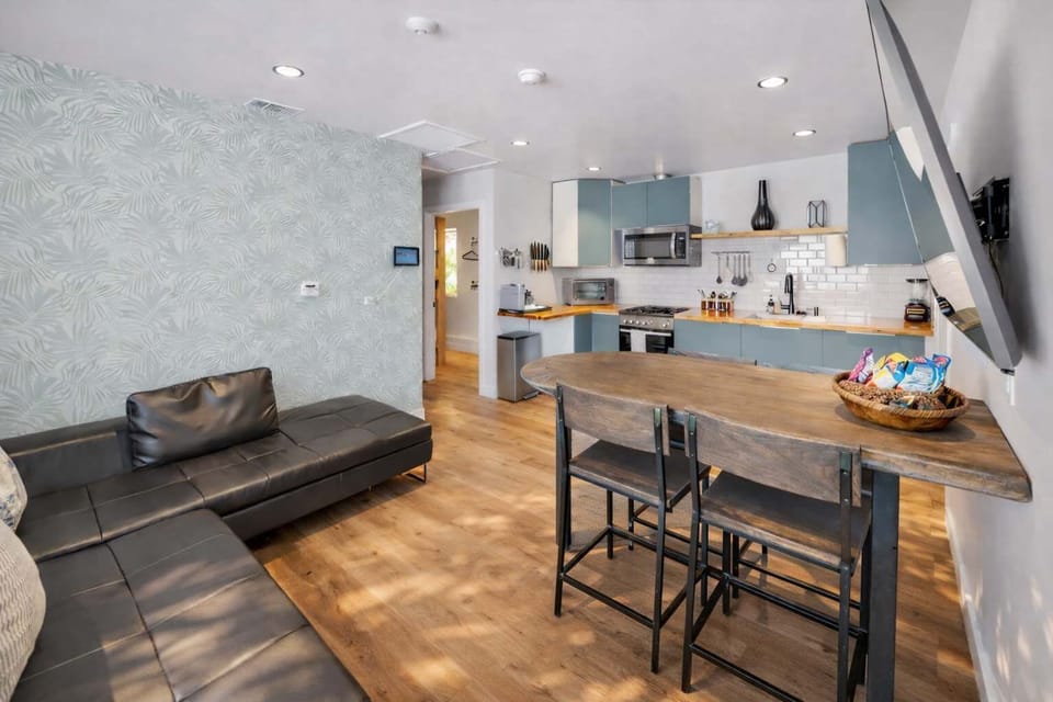 Spacious Open-Concept Living Area with Leather Sofa, Full Kitchen, and Dining Bar — Bright Coastal Comfort

