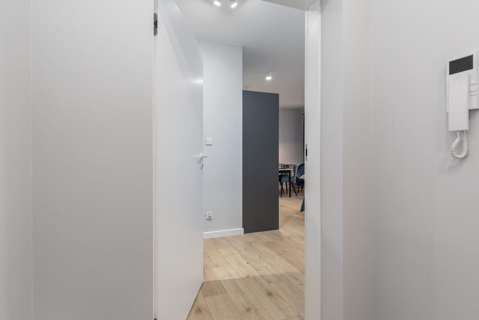 A hallway leading to the main entrance of the apartment, clean and minimalistic.

