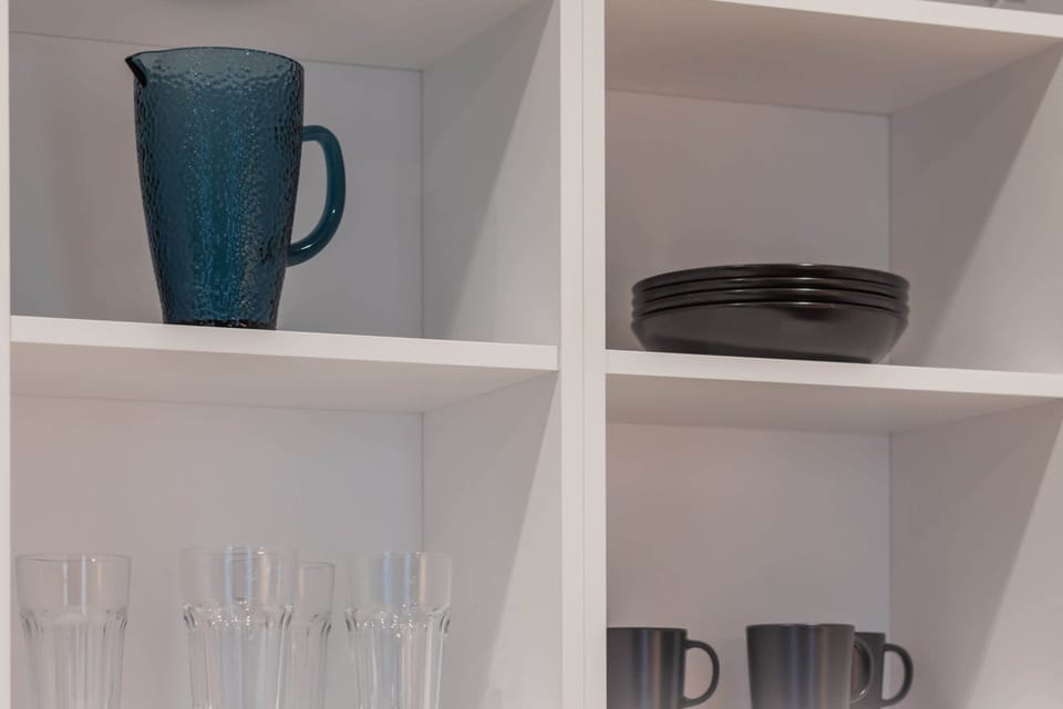 Shelving with neatly arranged dishes and decorative elements in a kitchen.
