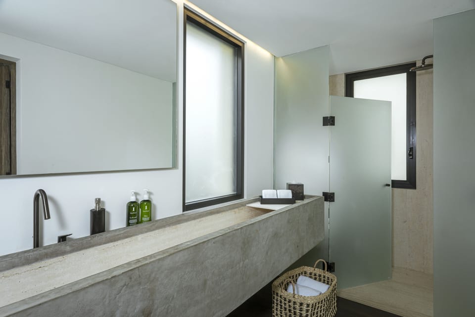 En-suite bathroom with a concrete trough vanity and walk-in shower at Villa Marena in Hacienda Beach, Cabo San Lucas.