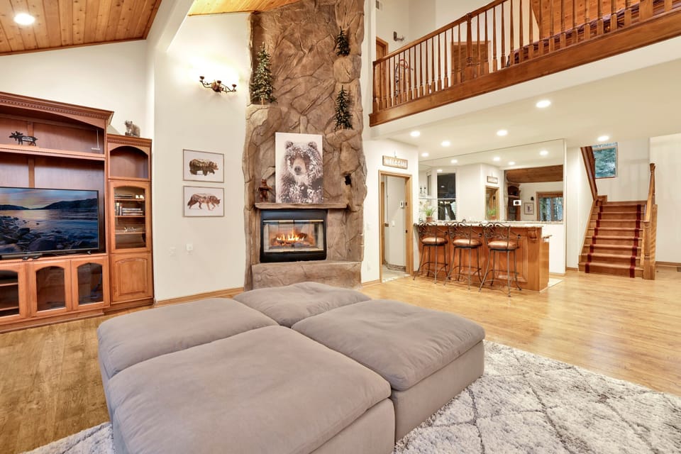 Cozy mountain living room with a stone fireplace, comfy seating, and smart TV—perfect for relaxing evenings, movie nights, and warm cabin vibes after outdoor adventures.