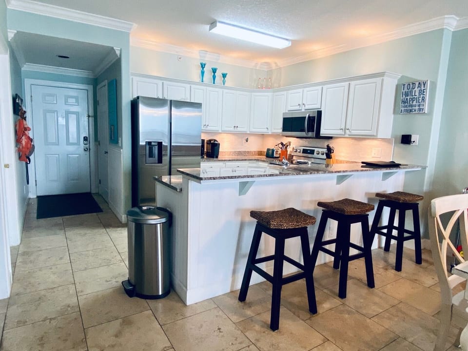 Modern well equipped kitchen with stainless appliances and a bar counter.   