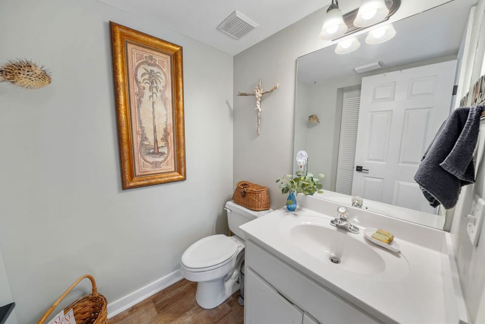 Your bright, coastal-themed bathroom features fresh white finishes, warm wood floors, and charming nautical touches that make your daily routines feel like seaside escapes.