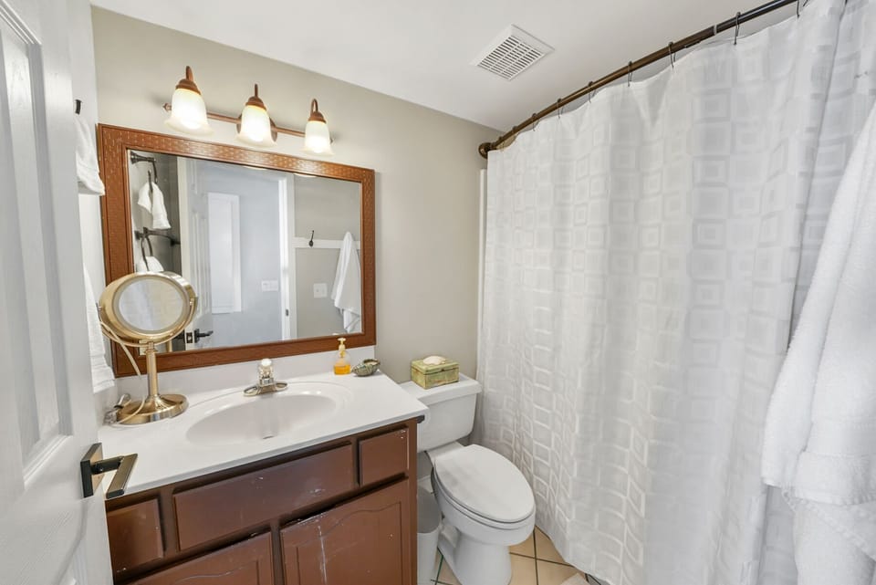 Your private bathroom features a full tub with shower, elegant vanity, and thoughtful touches like a magnifying mirror for your morning routine.