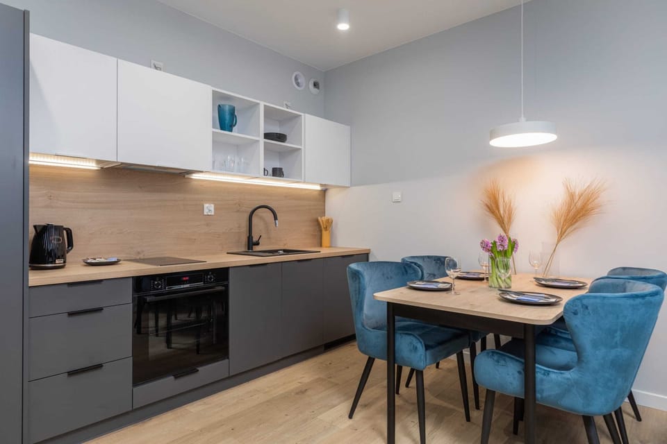 A kitchen and dining area with a modern design, showcasing blue upholstered chairs and elegant lighting.
