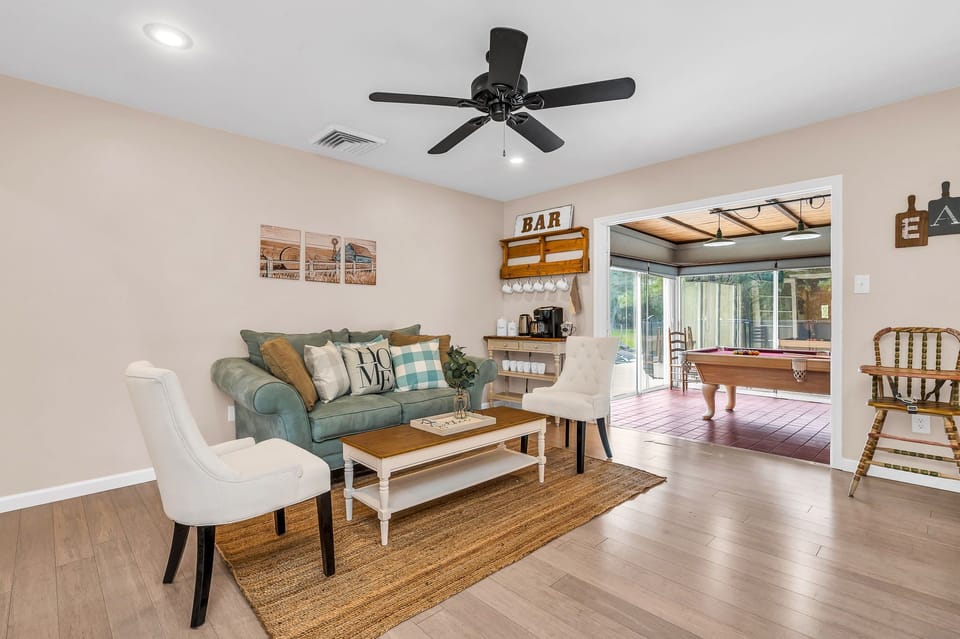 Just off the kitchen is a cozy seating area, with a light blue velvet loveseat, 2 high-backed chairs and a French-country coffee table, which sits on a natural jute rug.