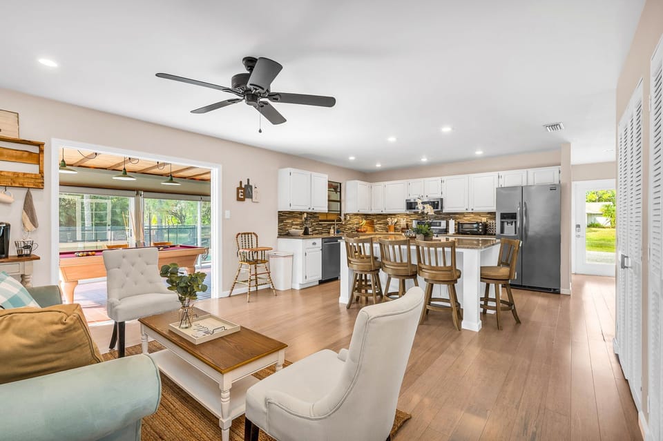 Just off the kitchen is a cozy seating area, with a light blue velvet loveseat, 2 high-backed chairs and a French-country coffee table, which sits on a natural jute rug.