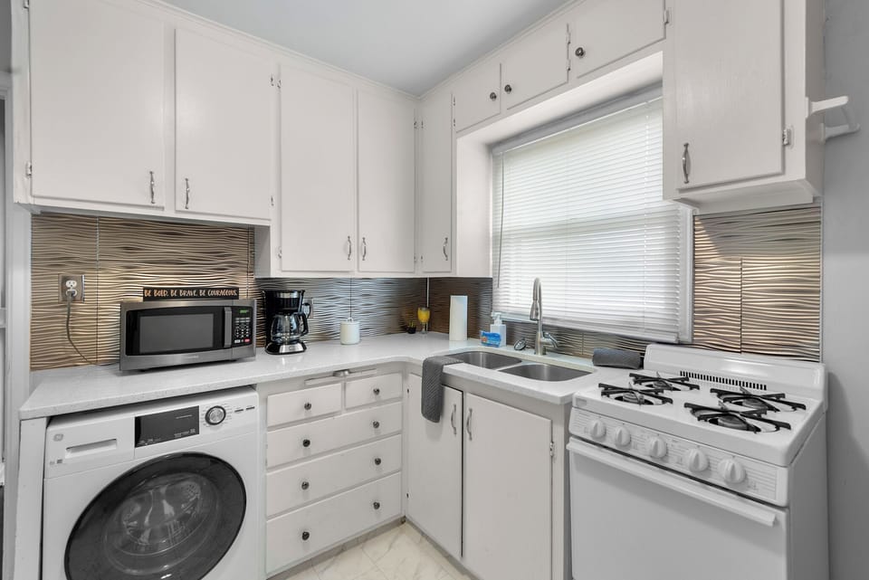 Kitchen with small 4 burner Stove and Oven, Clothes Washer, Microwave, Fridge, and Coffee Maker