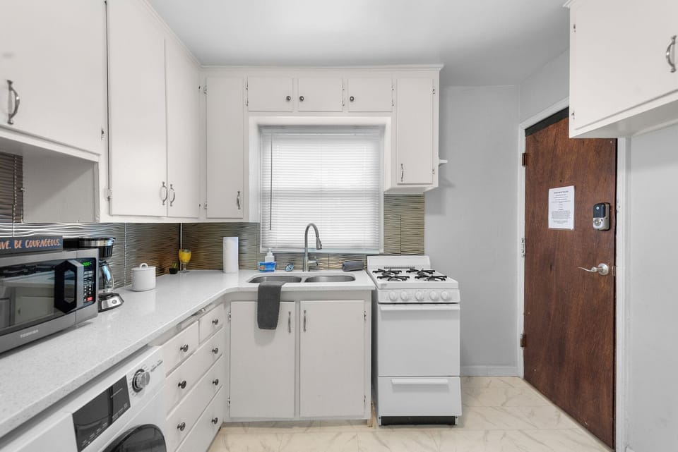 Kitchen with small 4 burner Stove and Oven, Clothes Washer, Microwave, Fridge, and Coffee Maker