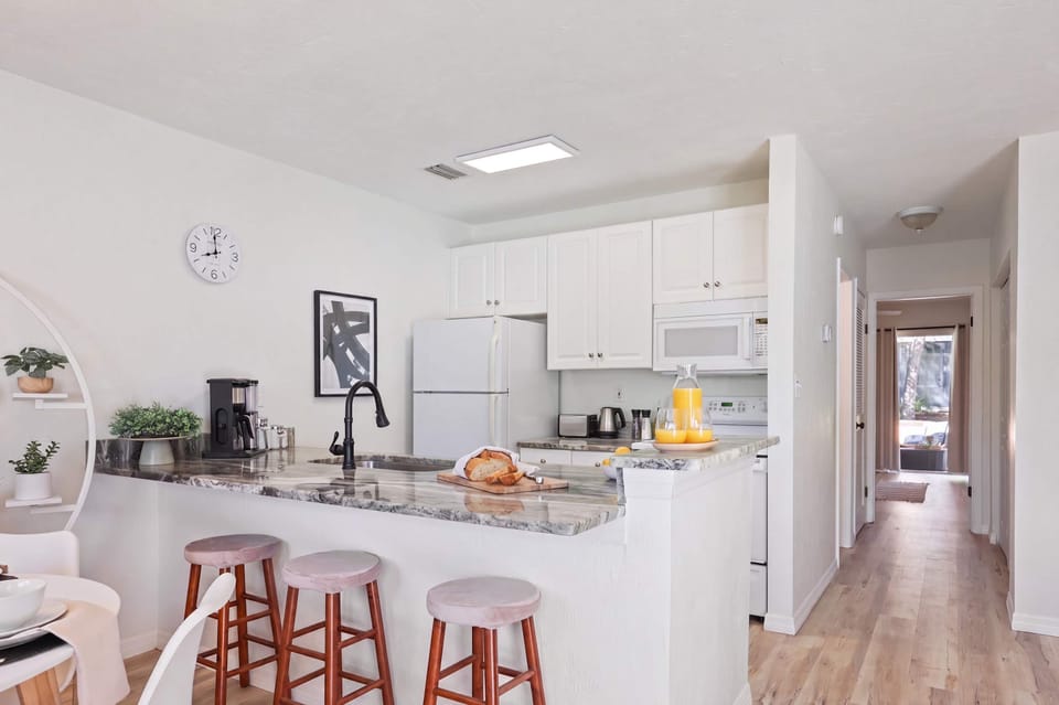 Start your morning with freshly squeezed juice at the sprawling granite breakfast bar. This fully equipped kitchen features crisp white cabinetry, modern appliances, and a seamless open layout that keeps you connected to the dining area.