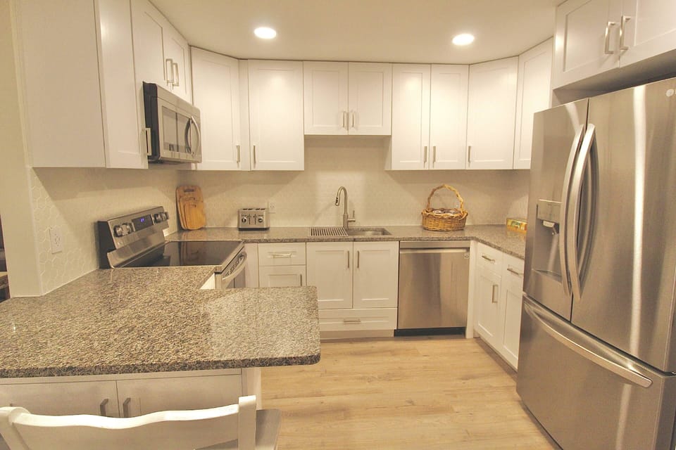New white cabinetry with stainless steel appliances.