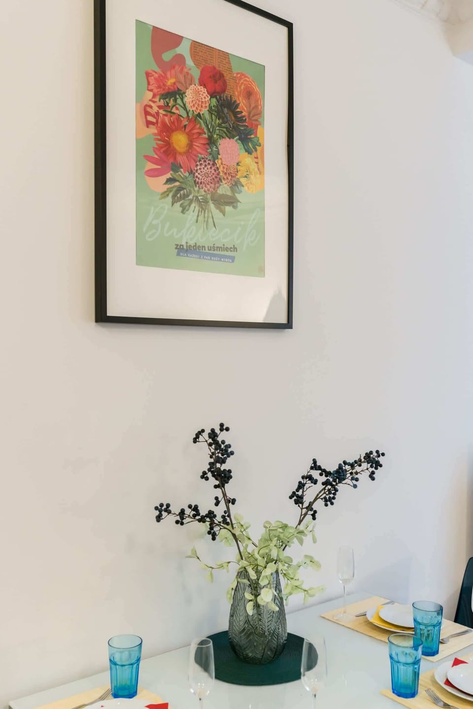 A cozy studio with a dining table, TV stand, and turquoise bedding complementing the space.
