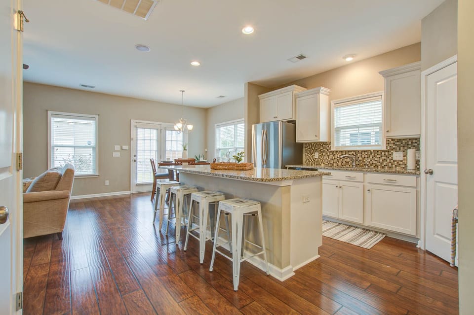 Bright open concept kitchen and dining area with granite island, hardwood floors