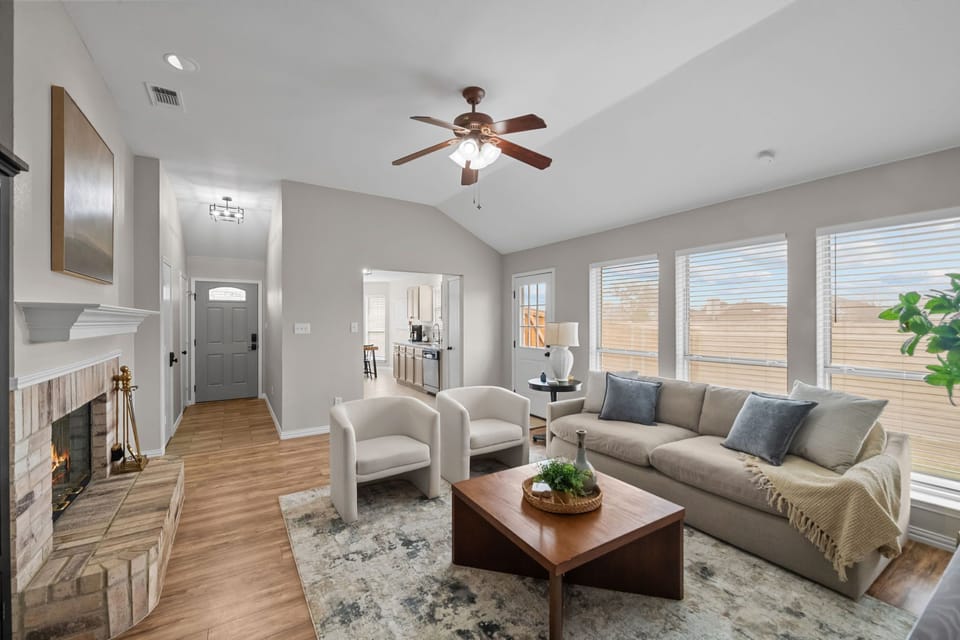 Bright and airy living room with plenty of seating, large windows, stylish furnishings, and warm wood accents. Perfect for relaxing!