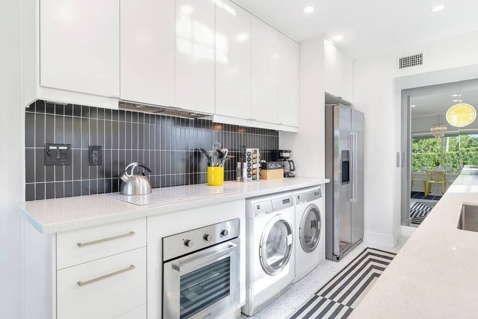 Modern kitchen with integrated washer and dryer and stainless steel appliances.
