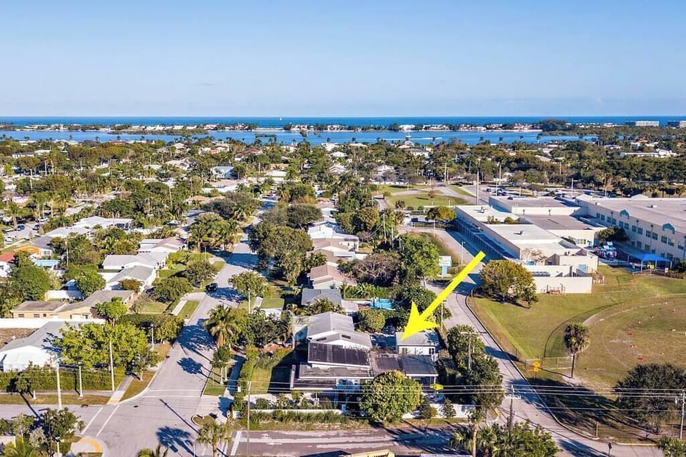 aerial view of the neighborhood with a yellow arrow pointing to the property near the coast