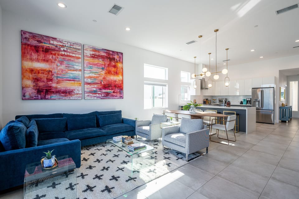 Modern high-ceiling living room with an open kitchen, sleek modern furniture, and a 75-inch TV