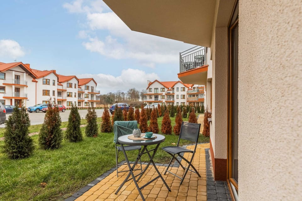 A charming balcony with a small table, chairs, and a view of the surrounding buildings.
