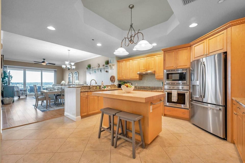 Cook & connect in the open kitchen w/ wood cabinetry, granite counters, & island seating.