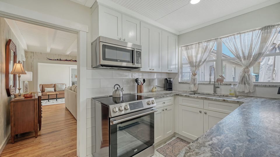 Kitchen corner featuring white cabinetry, stainless steel microwave, and stove