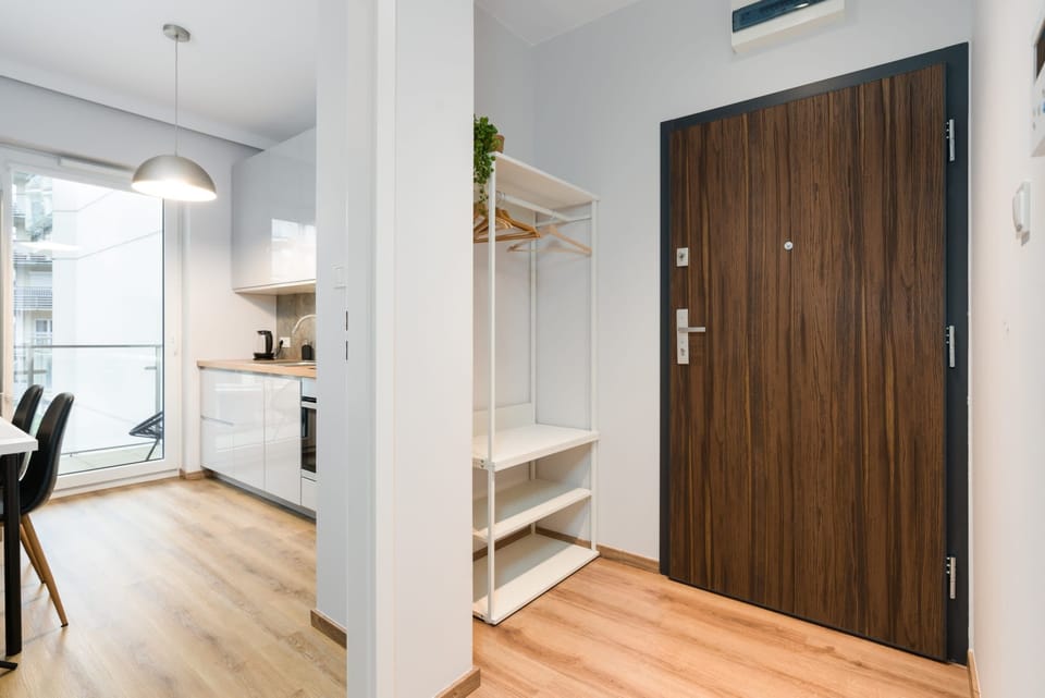A hallway with wooden flooring, a large wardrobe, and access to the apartment.
