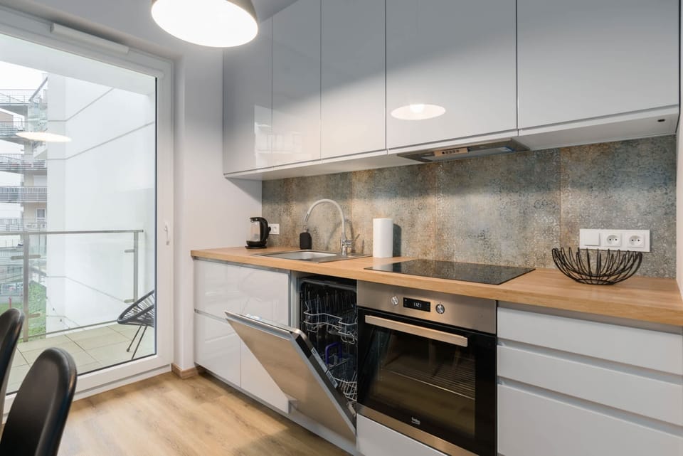 A kitchenette with sleek gray cabinets, a built-in oven, and a wooden countertop.
