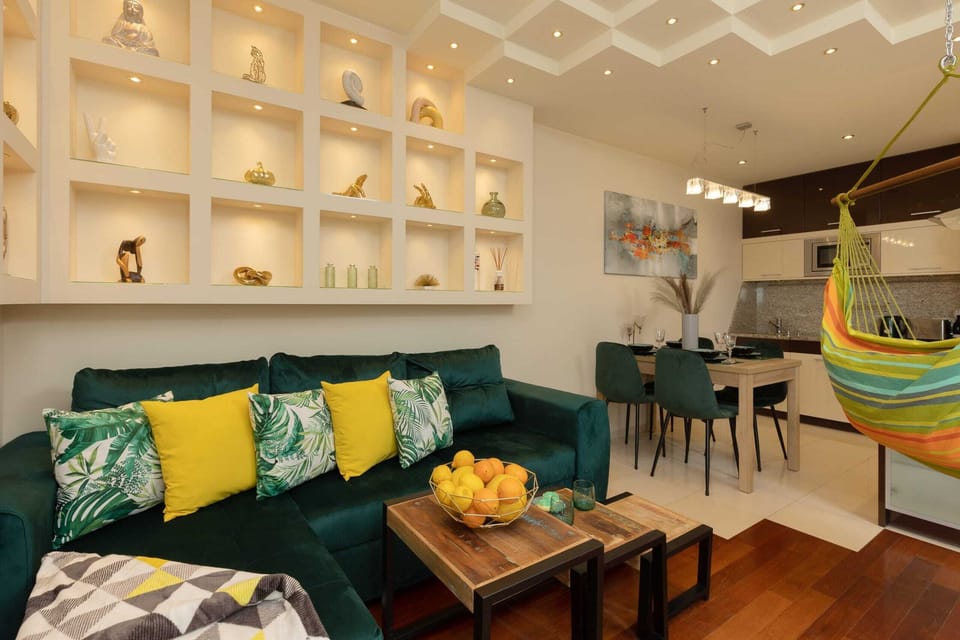 A living room with a green sectional sofa, vibrant cushions, and cozy lighting.
